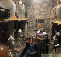 A cellar with demijohns, wine, and drinks, hidden in a stone cottage.