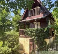A cottage in Jablonov nad Turňou surrounded by greenery, with a wooden balcony and climbing plants.