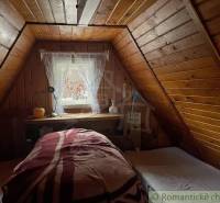 The attic of a wooden cabin with a skylight and cozy beds.