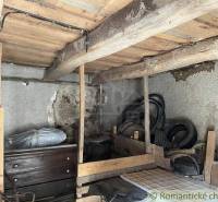 An old attic space contains furniture, a wooden structure, and electrical wiring of a family house.