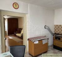 Interior of a family house with a kitchen, an old stove, and a view into the living room.