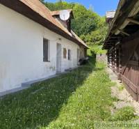 Traditional family house with wooden structure, garden, and greenery in the countryside.