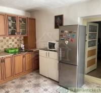 A kitchen in a family house with wooden cabinets, a sink, and a stainless steel refrigerator.