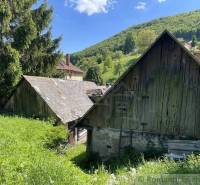 In a rural mountainous landscape, there is an ancient wooden house surrounded by nature.