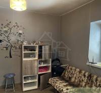 A room in a family house: a comfortable sofa, furniture, wall decoration, and a lamp.
