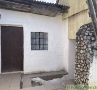 A cottage with white walls, wooden doors, and a stone wall on the terrace.