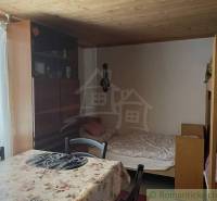 Room in a cabin with a wooden ceiling, bunk bed, and dining table.