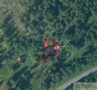 Aerial view of cabins surrounded by forest with highlighted plot for sale.