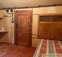 A wooden cabin with patterned bedding, wooden furniture, and walls create a rustic atmosphere.