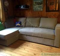The image shows a cozy room in a cabin with wooden walls and a comfortable couch.