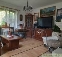 Living room with furniture, retro stroller, paintings, and a family house in a traditional style.