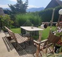 Garden and family house, benches, table, flowers, mountains in the background, lawn.