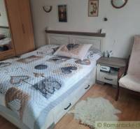 A comfortable bedroom containing a double bed, a wardrobe, and an armchair. Accessories adorn a cozy family home.