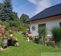 A family house in a garden with flowers, wood, and a lawn. Romantic cottages in the countryside.
