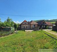 The picture shows rural houses surrounded by a garden and nature in a peaceful setting.