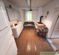 A kitchen with a wooden floor, a stove, and a table in a family house.