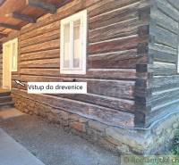 A log cabin with a stone foundation and a family house with steps leading to the entrance of the cottage.
