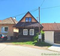 Stone house with a gable roof and a car on the driveway offers family comfort.