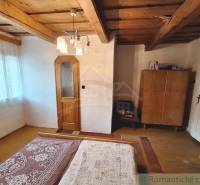 A cozy room with wooden beams and furniture in a family house is visible.