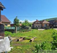 In the picture, there is a rural village, family houses, a garden, a clear sky, and greenery of the landscape.