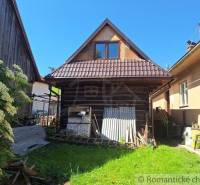 A rustic family house with a garden, wooden elements, and a large shrub for a peaceful atmosphere.