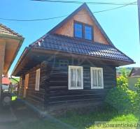 A traditional wooden house with windows and an attic in a sunny setting, a family home in the village.