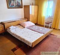 A bedroom in retro style with wooden furniture, a carpet, and a family house complements the cozy atmosphere.
