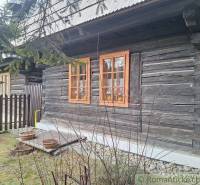 A traditional wooden family house surrounded by nature and a fence, with a rustic atmosphere.