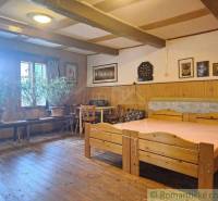 Traditional wooden interior with furniture, flowers, and a family house with historical decorations on the walls.