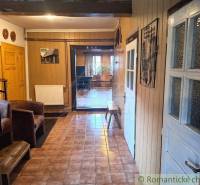 A hallway of a family house with wooden moldings, tiles, and furniture, leading to the living room.