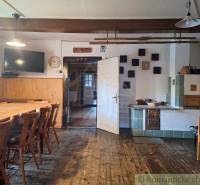 A country kitchen in a family house with wooden furniture, a stove, and a television.