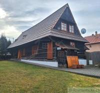 A traditional wooden house, a family home, has a sloped roof and wooden shutters in the village.