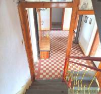 The interior of a family house with a checkered floor, wooden walls, and a staircase with a railing.