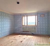 A room with a wooden floor, wallpaper, and an open window in a family house.