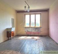 An abandoned family house with wooden floors, worn-out walls, an old chandelier, and an empty interior.