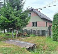 The picture shows a family house surrounded by trees and a fence.