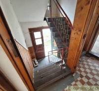 Staircase and entrance door in a family house with wooden paneling and tiles.