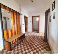 Entrance hall with a bench, mirror, tiles, and pictures in a family house.