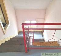 A staircase with a red railing in an older family house, with light coming through the window.