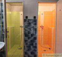 An interior with two shower cabins in colored tiles: green and orange. Commercial spaces.