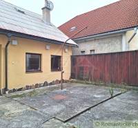 Courtyard with a reinforced surface, yellow building facade, red tiled roofs, commercial spaces.