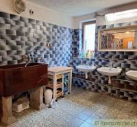 Rustic bathroom with sinks, wooden cabinet, and dark wall tiles.