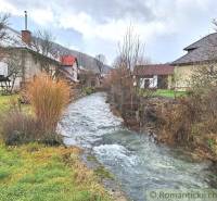 A stream flowing between family houses in a natural rural environment.