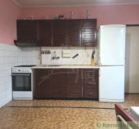 A kitchen with a traditional dark kitchen unit, refrigerator, sink, and stove in a family house.
