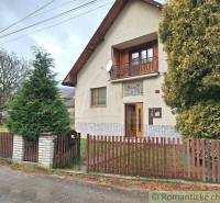 Family house with a balcony and a landscaped garden. Wire fence, tree nearby.