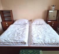A bedroom with simple beds, nightstands, and a lamp, suitable for a family house.