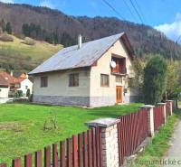 A family house with a wooden fence, a large garden, surrounded by mountains and surroundings.