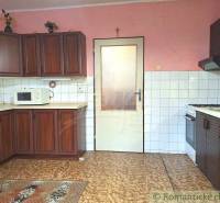 A kitchen in a family house with classic wooden cabinets and white tiles.