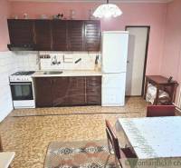 A kitchen with a gas stove, a white refrigerator, Roman blinds, and a family house with pink walls.