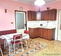 A kitchen in a family house with wooden cabinets, a table, and pink walls.